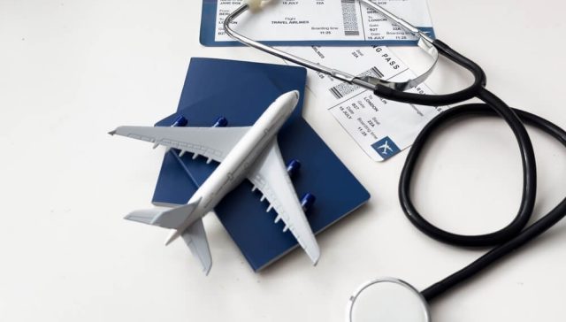 Passport, boarding pass, and medical equipment representing Covered California coverage for urgent care and medical emergencies while traveling out of state.
