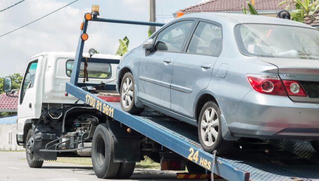 Car loaded onto a tow truck, illustrating potential damage from towing and insurance coverage