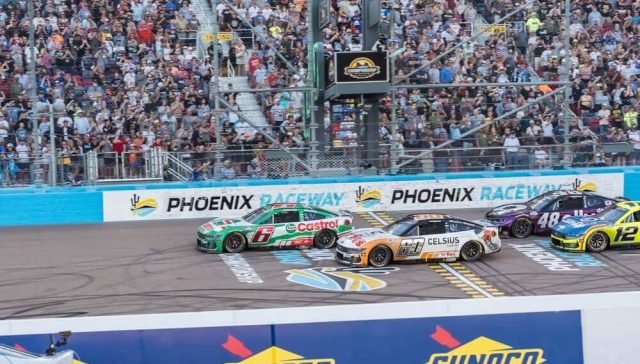 Phoenix Raceway strategic track action as NASCAR cars race toward the finish line in front of packed grandstands.
