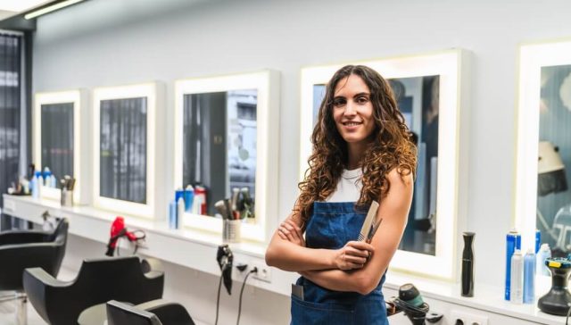 Salon beauty professional standing at her workstation with hair styling tools.