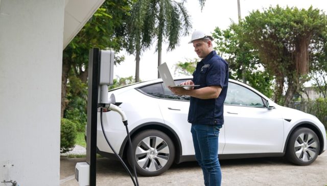 Technician installing an EV charger at home, highlighting home insurance considerations for EV charger installation.