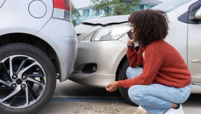 Woman calling after a minor collision, preparing to file a small auto insurance claim.