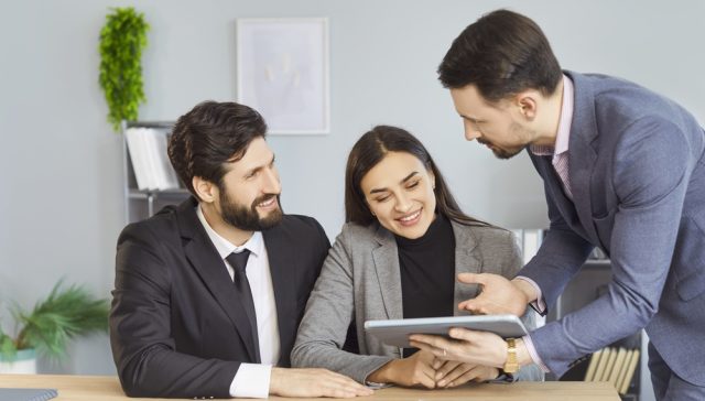 Insurance agent reviewing policy information with clients on a tablet.