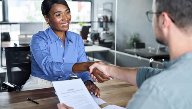 Independent agent shakes hands with a client while reviewing paperwork, helping drivers shop for high-risk auto coverage through an independent agent.