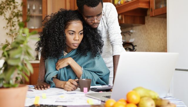 Couple reviewing household expenses on a laptop while looking to find affordable car insurance.