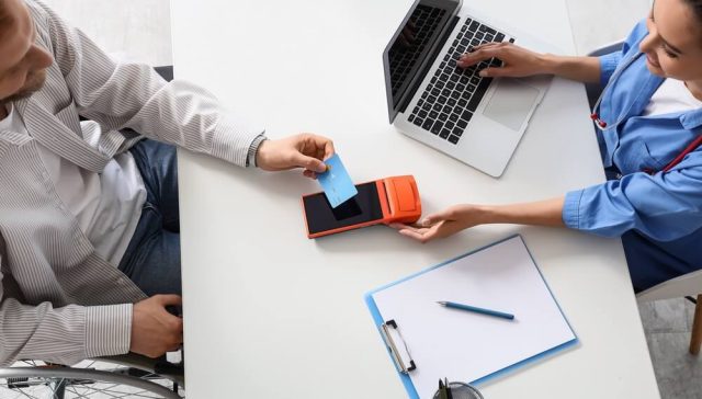 Customer paying by credit card at a medical office, illustrating the choice to pay in full or monthly.