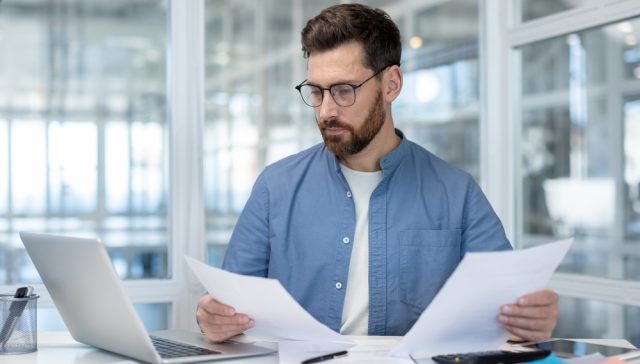 Man reviewing documents at a desk while evaluating a renters insurance company.