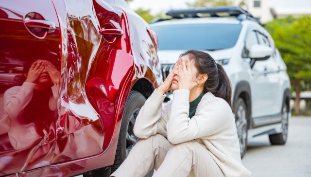 Woman reacts to vehicle damage while preparing to file diminished value claims after an auto accident.