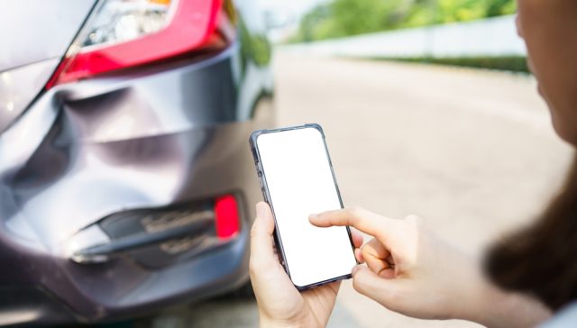 Person using a smartphone to file a car insurance claim after a rear-end collision.